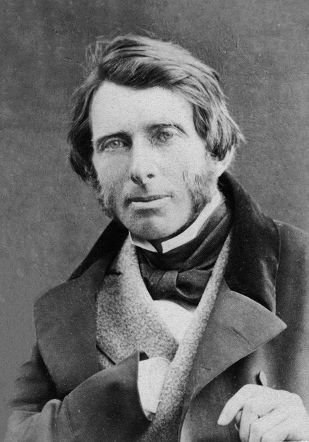 Photographic portrait of John Ruskin in 1863, seated, bearded, gazing to the side.