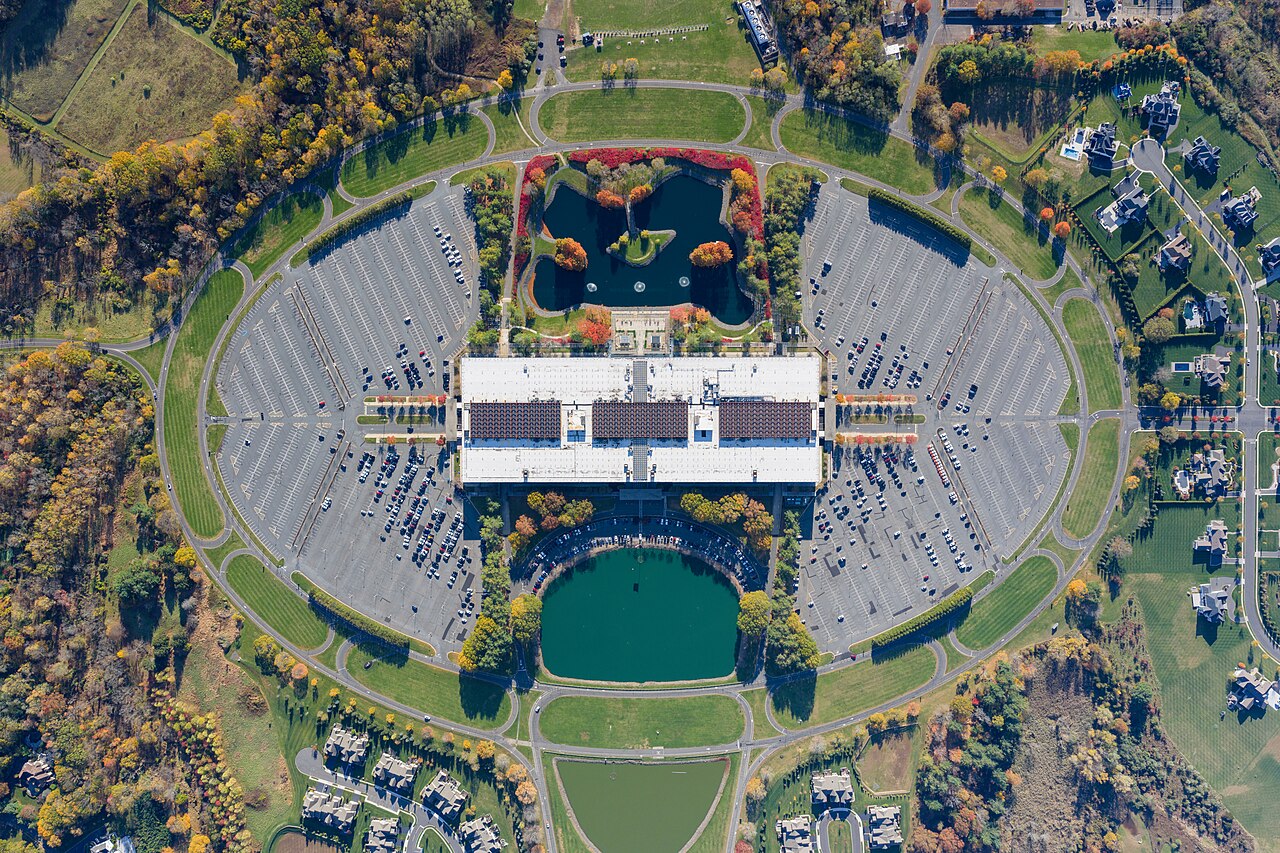 Top-down aerial view of the vast Bell Works complex, a long rectangular building surrounded by parking and grounds.