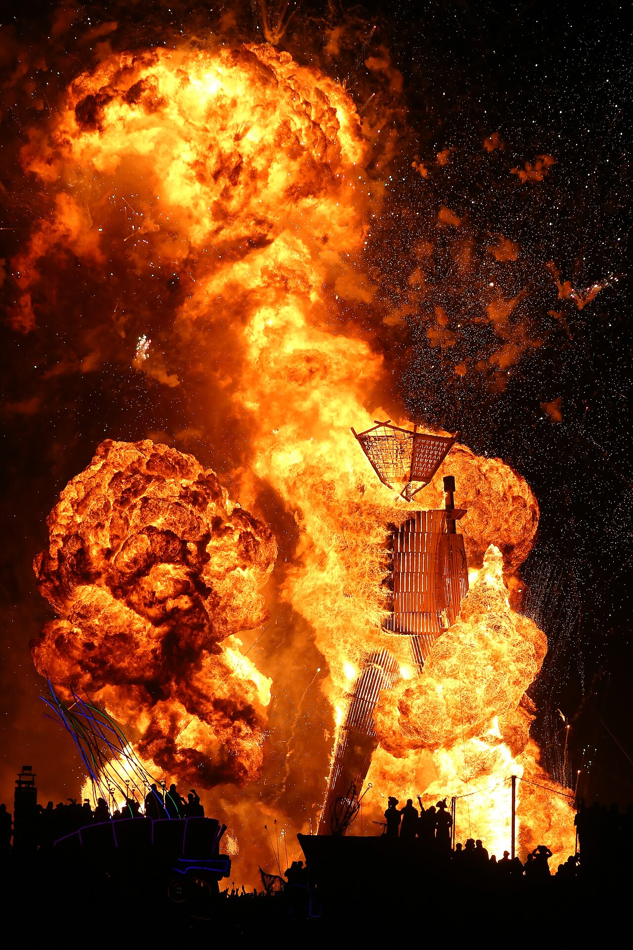 The Man, a tall wooden effigy, engulfed in flame against the night sky at Burning Man 2014.