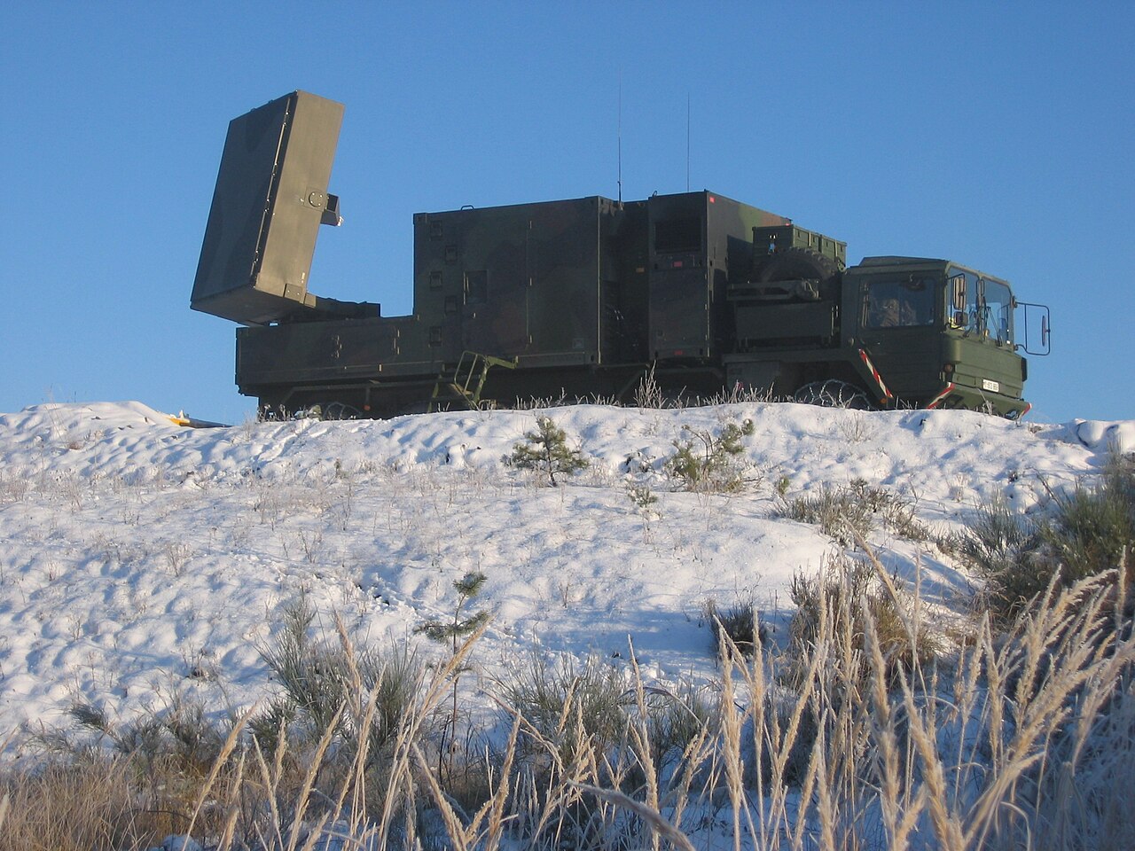 A large green-camouflaged military artillery-locating radar unit on a trailer, labelled COBRA.