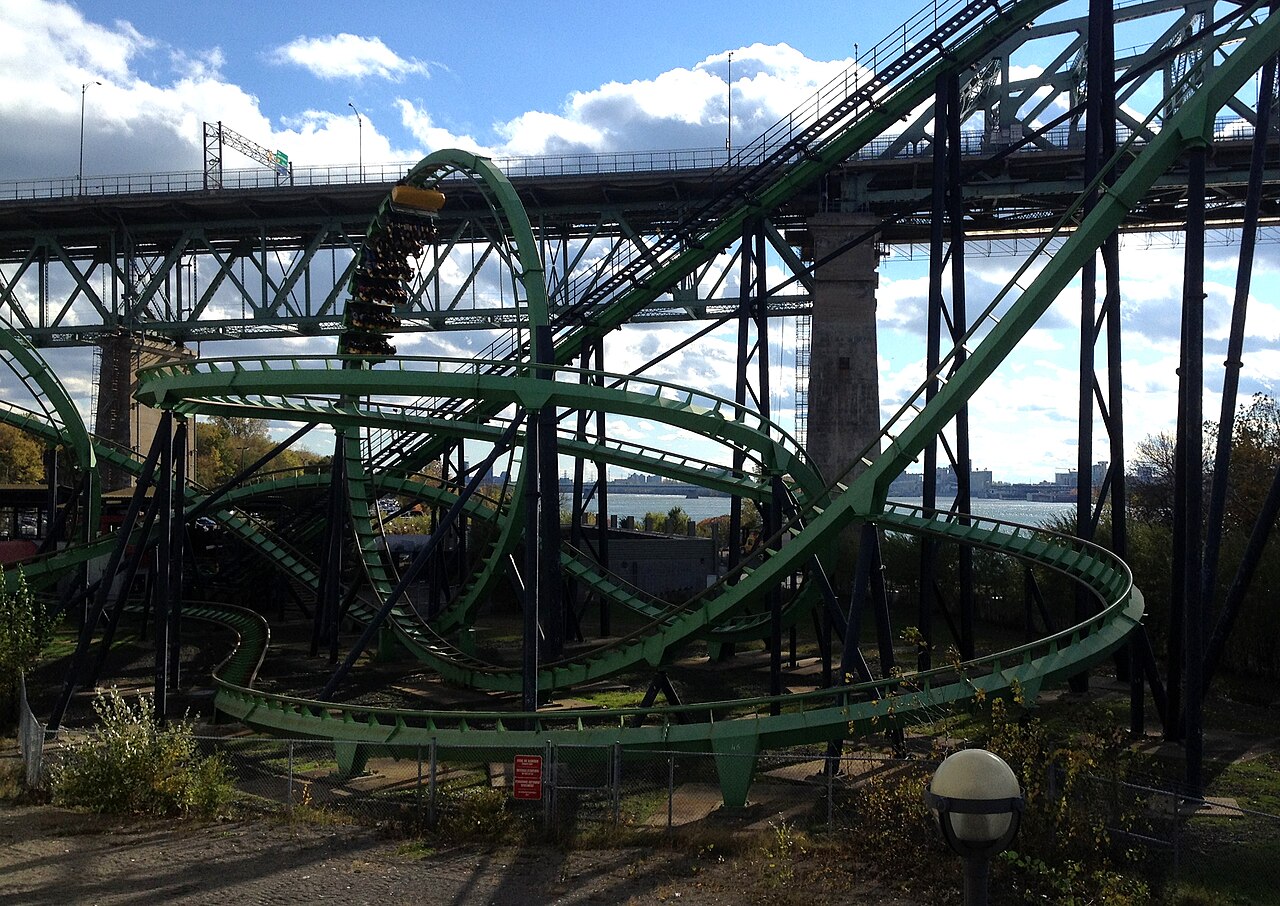 A looping steel roller-coaster named Le Cobra against a bright sky at an amusement park.