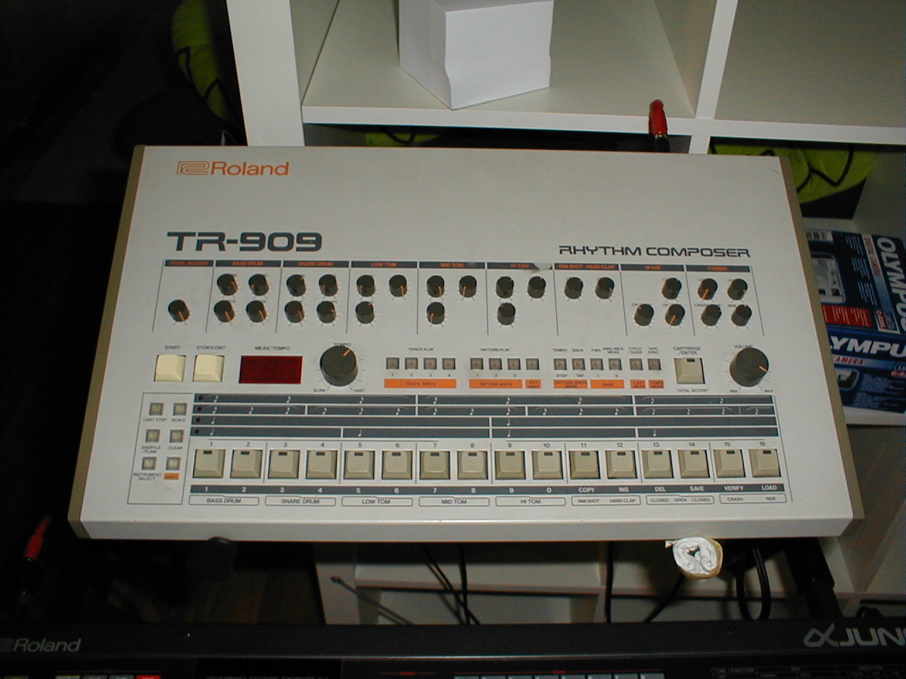 A Roland TR-909 rhythm composer viewed at an angle, showing its rows of colored pattern buttons.