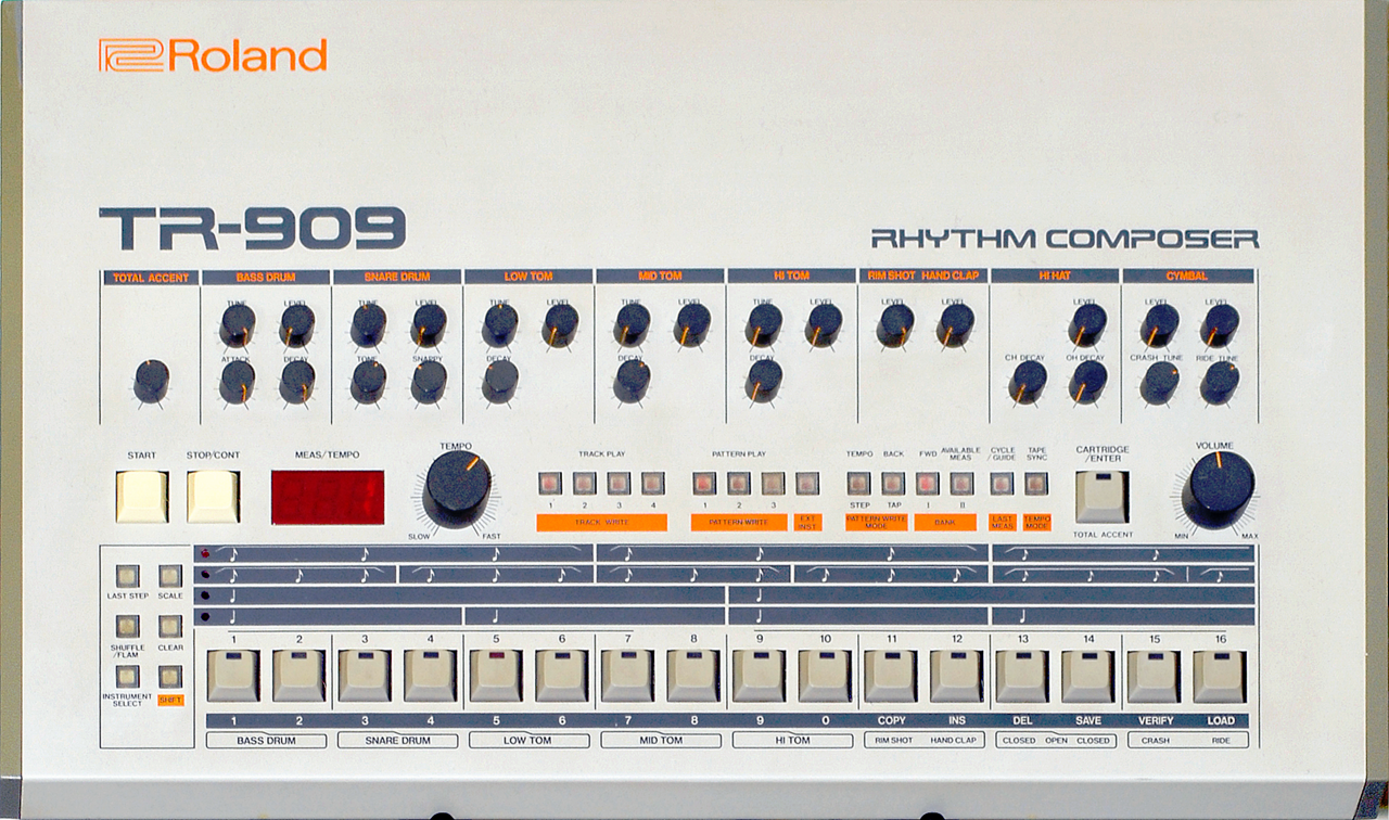 A Roland TR-909 drum machine, its silver front panel lined with white step buttons and orange accent controls.