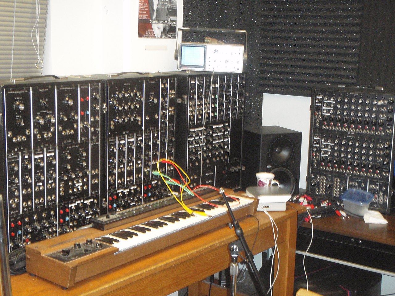 A large modular Moog synthesizer, a wall of patch cables and knobs, with an extra sequencer module beside it.
