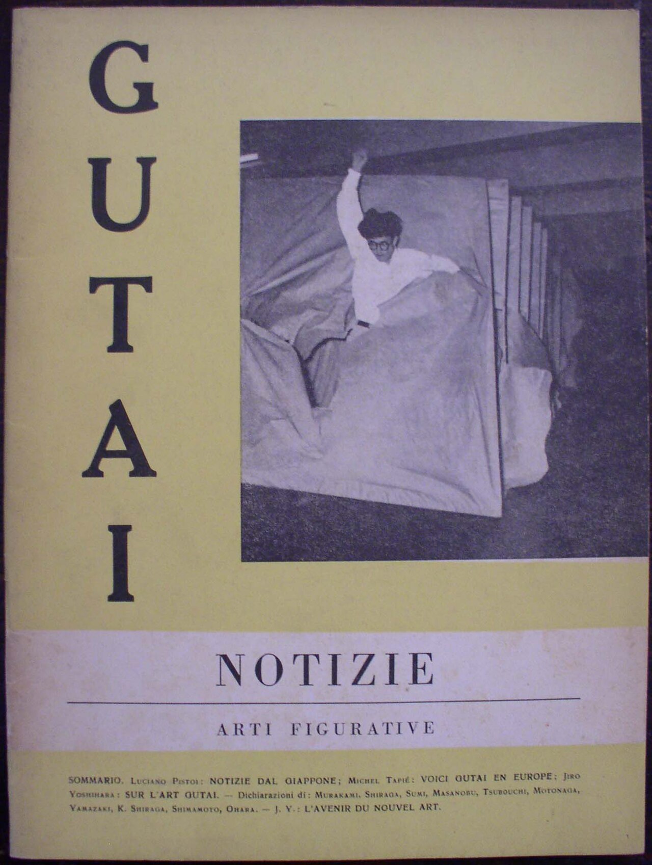 Cover of the journal GUTAI (Italian edition, 'Notizie / Arti figurative'), 1959: on an acid-yellow ground, giant vertical serif letters spell GUTAI beside a black-and-white photograph of an artist bursting through stretched paper screens.