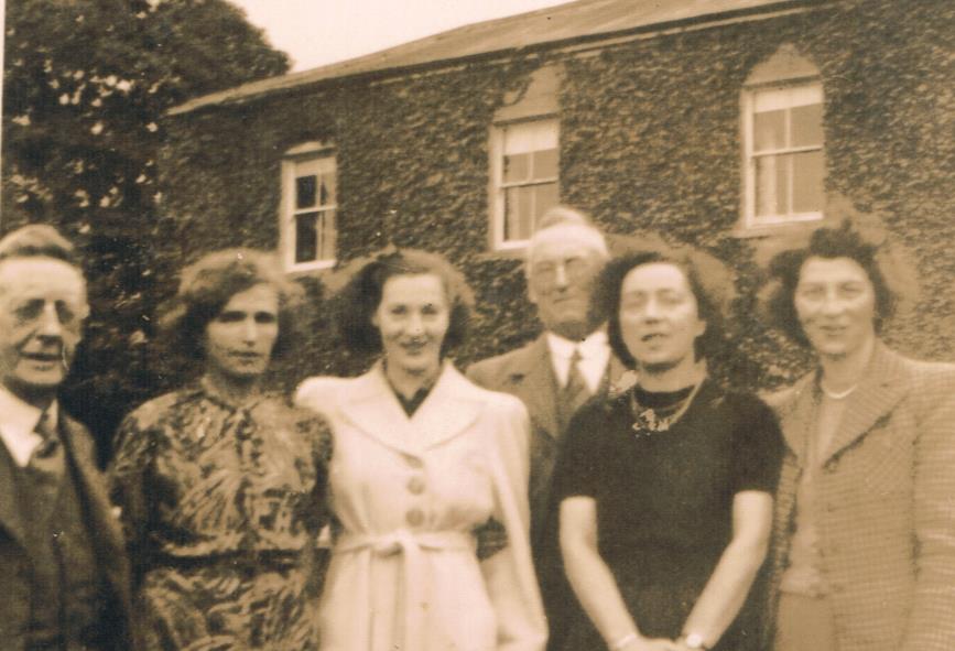 Sepia group photograph of six people standing before an ivy-covered house in 1951, Tolkien among them.