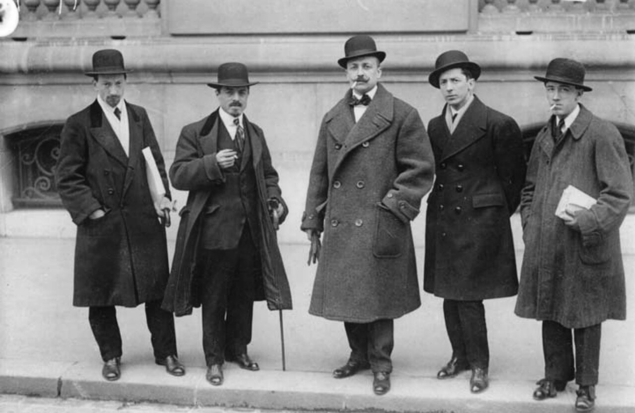 Black-and-white photograph, Paris 1912: Russolo, Carrà, Marinetti, Boccioni and Severini in overcoats and bowler hats outside the offices of Le Figaro.
