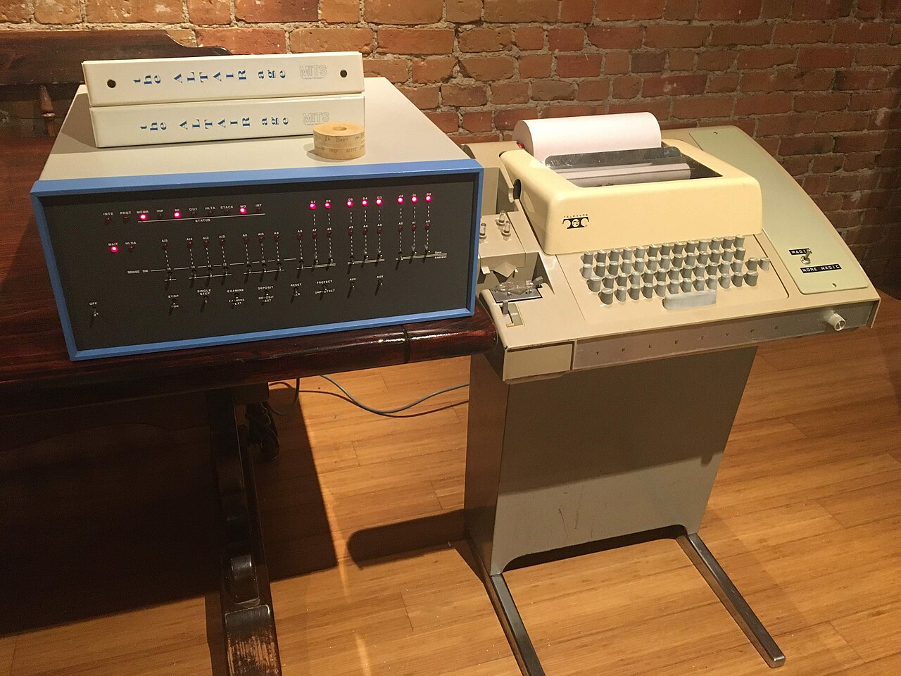 A kit-built 1975 Altair 8800 computer, its front panel covered in toggle switches and lamps, sitting beside a Model 33 ASR Teletype used as its terminal.