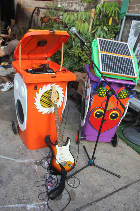 A homemade sound system built into wheelie bins, stacked in performance mode with a 12-volt mixer, outdoors.