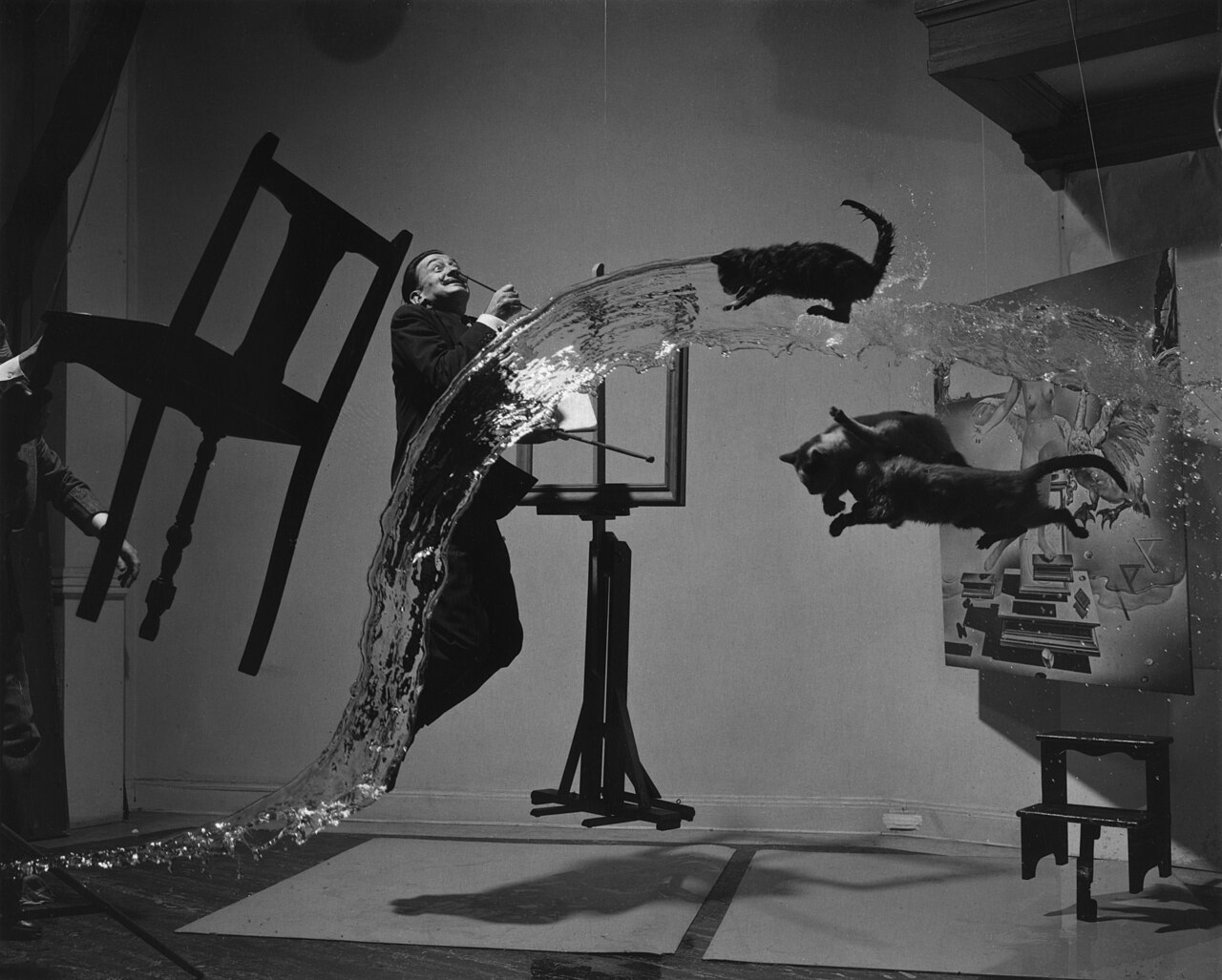 Dalí Atomicus — Salvador Dalí, three cats, a chair, an easel and a stream of water all suspended in mid-air in a single leaping composition.
