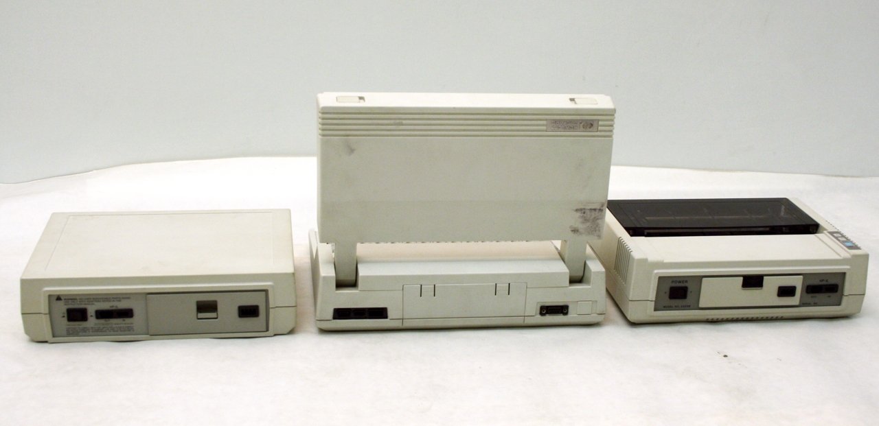 Rear view of the same folded beige HP portable computer and its two companion peripheral units, showing ports and switches.