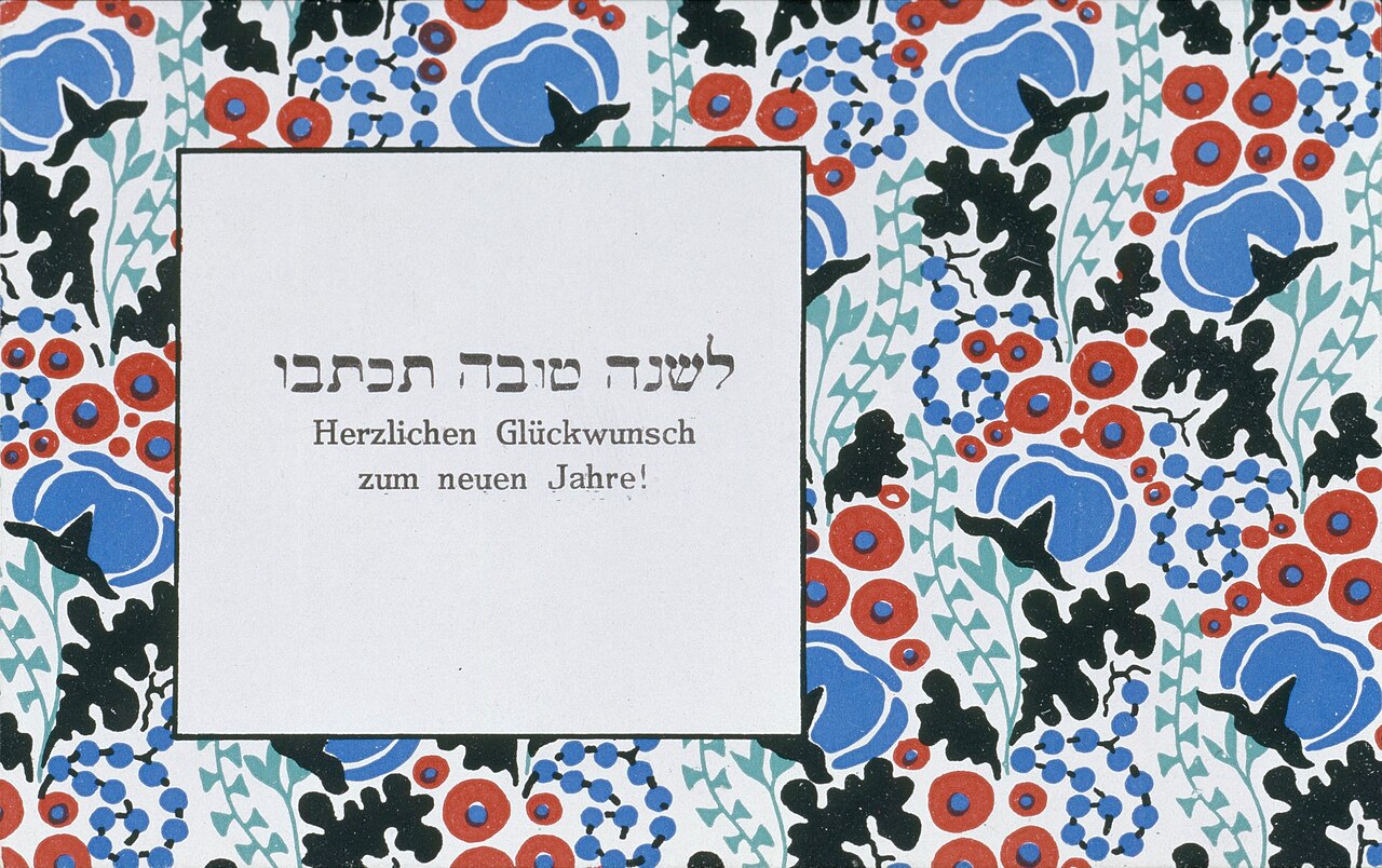 Wiener Werkstätte New Year greeting card: dense pattern of red poppies, blue blooms and black birds framing a white lettered panel.