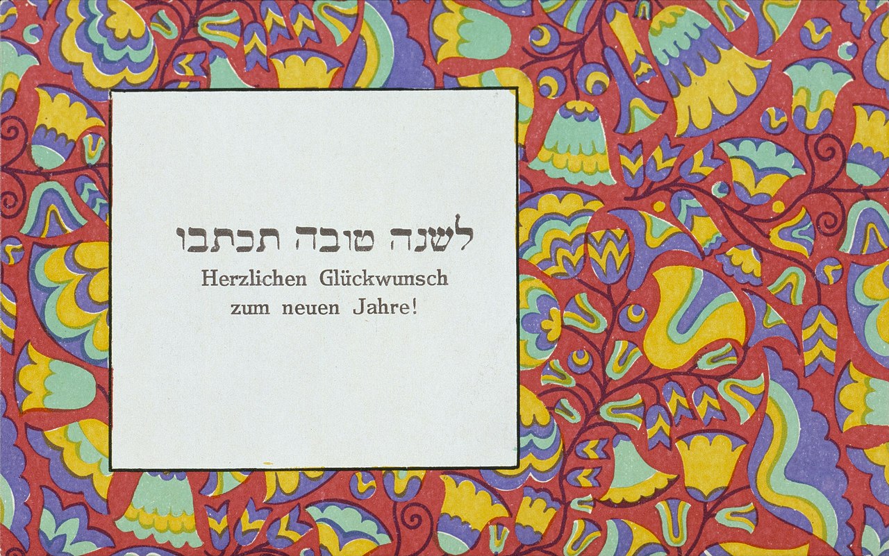 Wiener Werkstätte New Year greeting card: dense red, yellow, green and violet folk-inflected floral pattern around a white lettered panel.